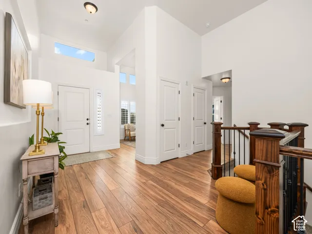 Expansive entryway featuring vaulted ceilings, transom windows, wood-finish flooring, a solid core entry door, and a staircase with wood newel posts and wrought iron balusters