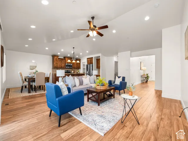 Spacious open-concept living area featuring wood-finish flooring, vaulted ceilings, and recessed lighting