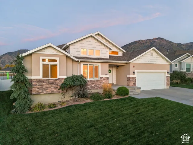 Exterior features a multi-level design, attached two-car garage, stone accent siding, and mature landscaping