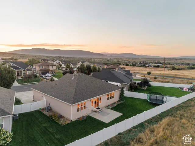 Expansive backyard featuring a manicured lawn, concrete patio, and white privacy fencing