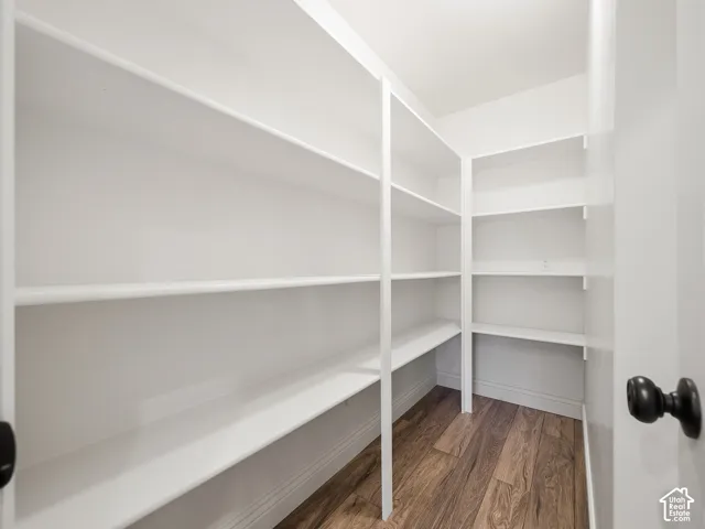 Walk-in pantry featuring expansive white shelving and wood-finish flooring