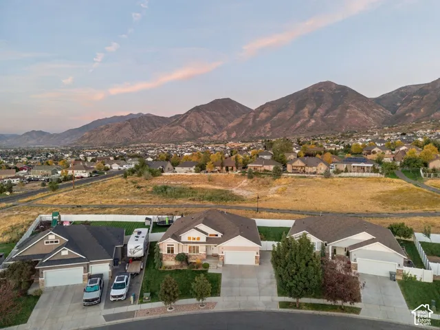 Neighborhood with multiple single-story homes, expansive mountain backdrop, and paved roads