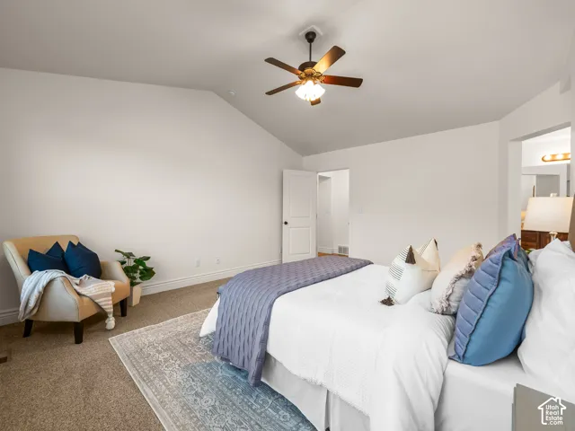 Vaulted ceiling, ceiling fan with integrated lighting, neutral wall finishes, carpeted flooring, and a white interior door
