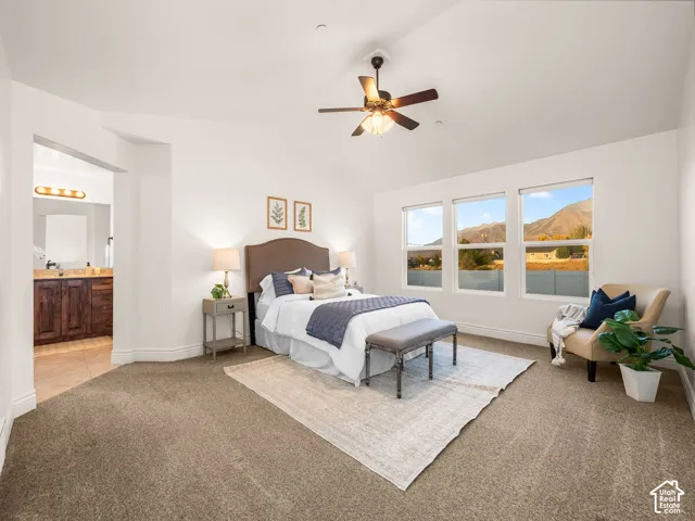 Vaulted ceiling with ceiling fan, triple windows, plush carpet flooring, recessed lighting, and an attached bath with dark wood-finish cabinetry and a single vanity