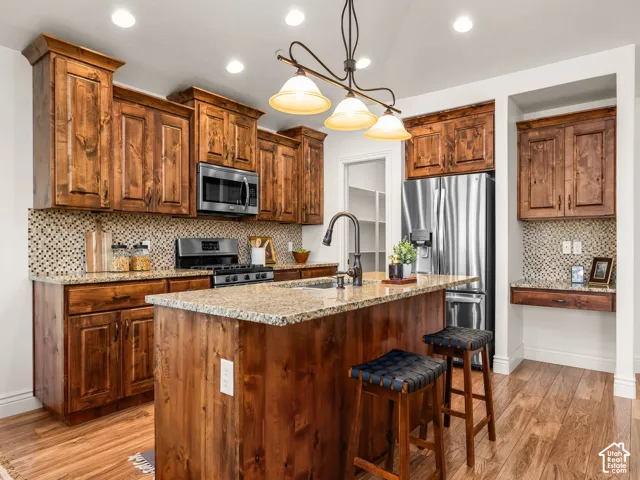 Kitchen featuring wood-finish flooring, custom wood cabinetry, granite countertops, and stainless steel appliances