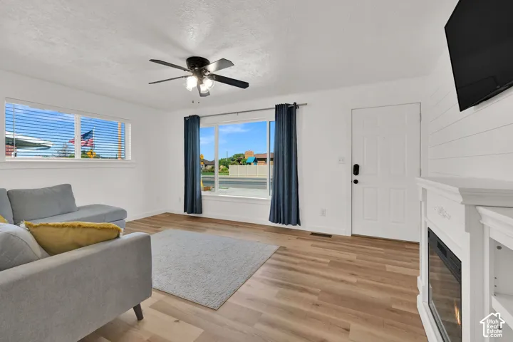 Wood-finish flooring throughout, white paneled door, and a white mantel with an electric fireplace