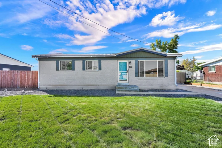Stucco exterior with a pitched roofline, front lawn, and paved driveway