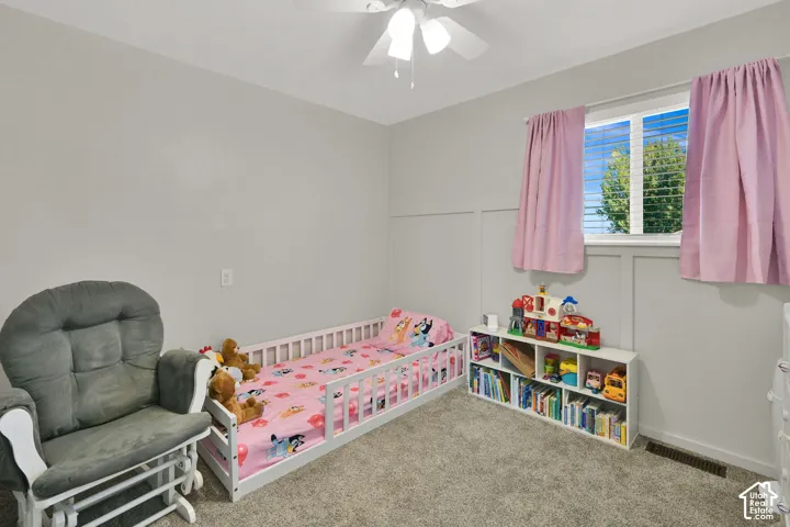 Carpeted flooring, ceiling fan, board and batten wall detailing, and a window with blinds