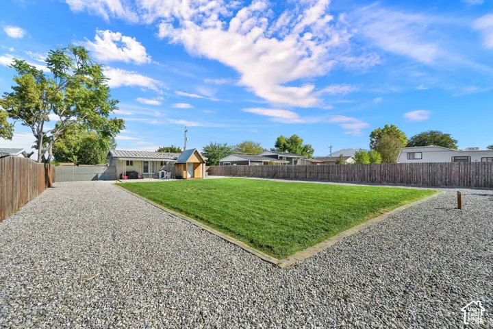 Expansive outdoor space featuring a large gravel area, a manicured lawn, and perimeter fencing