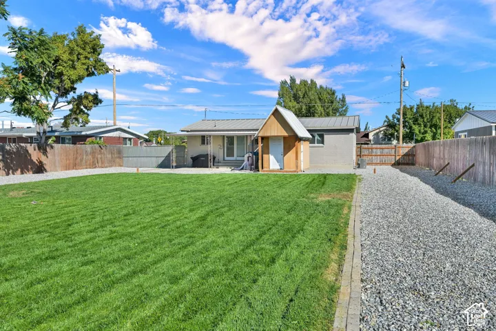 Expansive grass lawn, gravel path, wood privacy fencing, detached storage shed, and a rear patio