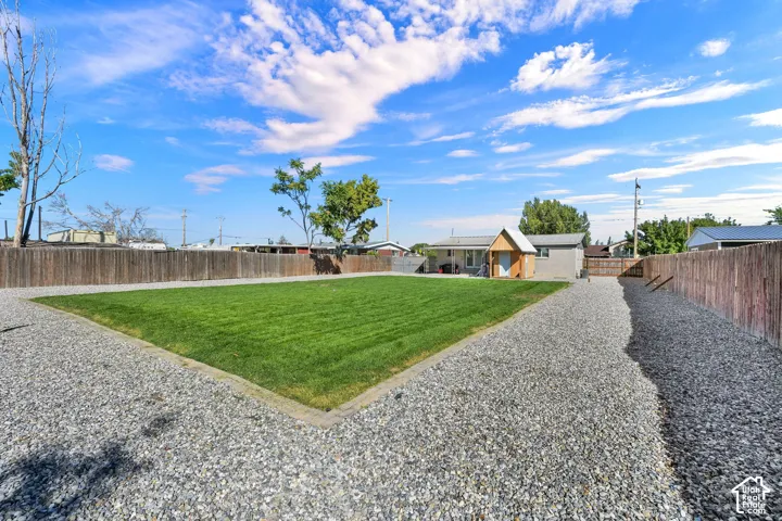 Expansive gravel lot with a central grass area, full privacy fencing, and an additional detached structure