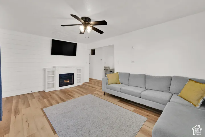 Wood-finish flooring with a white shiplap accent wall, built-in fireplace, and integrated shelving