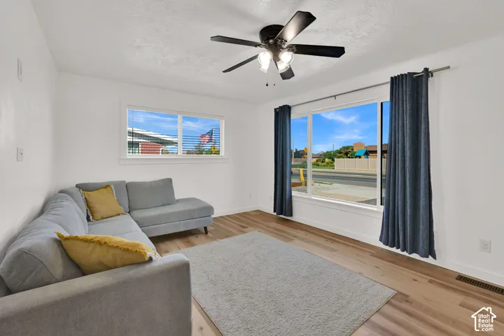 Bright interior with wood-finish flooring, white walls, and a black ceiling fan