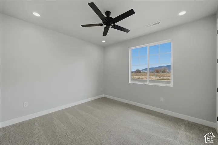 Recessed lighting, a ceiling fan, a window with a mountain backdrop, and light gray wall paint