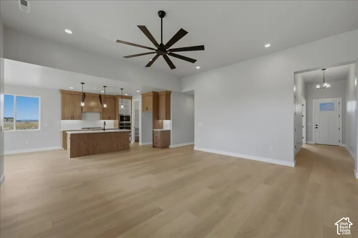 Expansive open-concept living area featuring light wood-finish flooring, recessed lighting, and a modern ceiling fan
