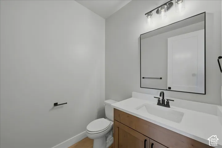 Powder room featuring a single vanity with wood-finish cabinetry, white countertop, and rectangular undermount sink