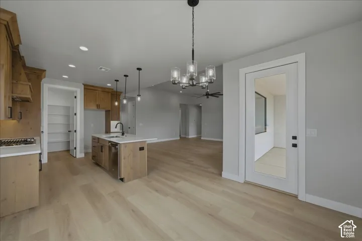 Kitchen featuring light wood-finish cabinetry, a central island with an integrated sink, and stainless steel appliances