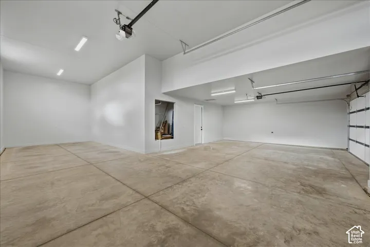 Spacious garage featuring a concrete floor, bright overhead lighting, and an overhead garage door