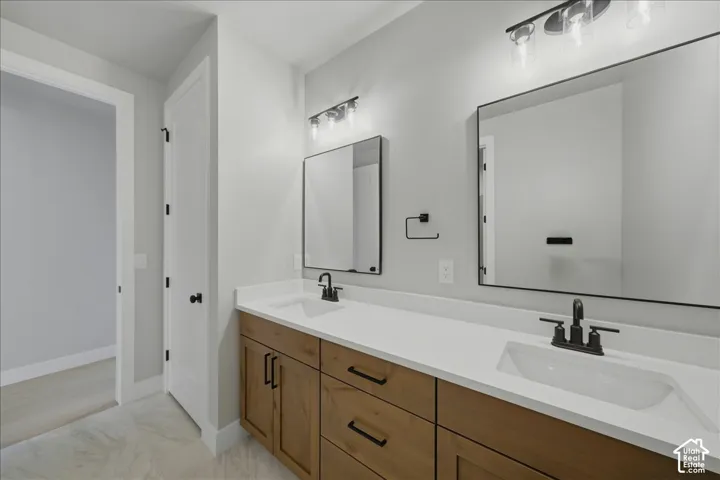 Double vanity with light wood-finish cabinetry, white countertop, and integrated sinks