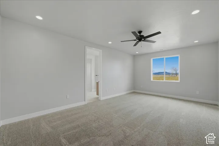 Recessed lighting, ceiling fan, neutral wall paint, carpet flooring, and a large window