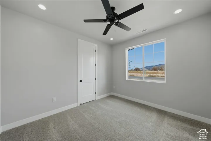 Recessed lighting, ceiling fan, white paneled door with black hardware, carpeted flooring, and a large window