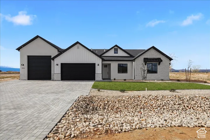 Contemporary exterior with a two-car garage, contrasting dark trim, and a paver driveway