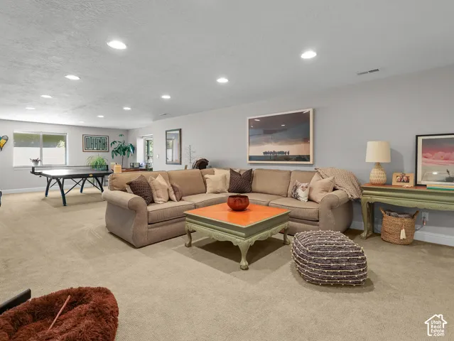 Expansive carpeted area with recessed lighting, offering ample space for various activities
