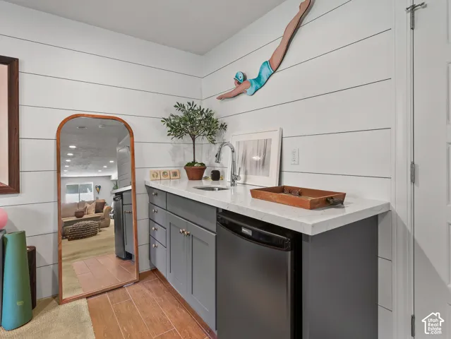 Wet bar featuring a stainless steel sink, contemporary faucet, quartz countertop, and under-counter refrigerator