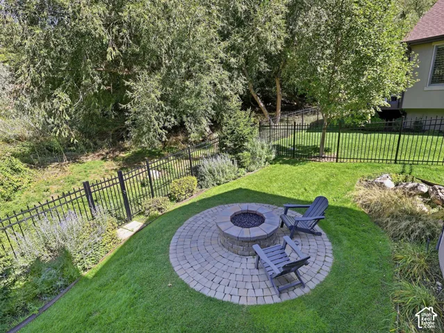 Manicured backyard with a circular paver patio and a built-in fire pit