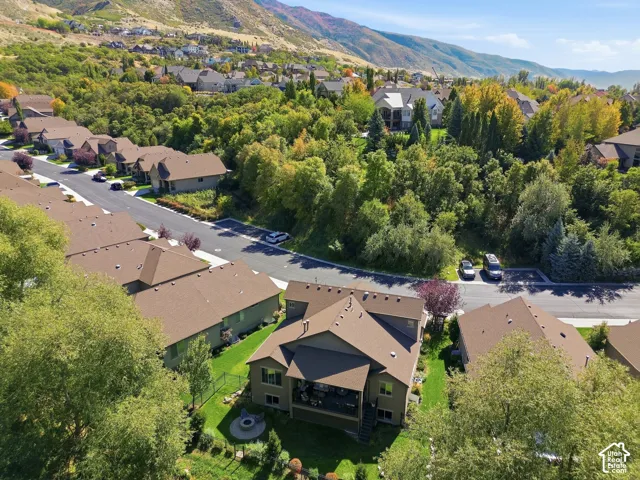 Residential property with a covered patio, tiered landscaping, and a fire pit feature, all surrounded by mature trees