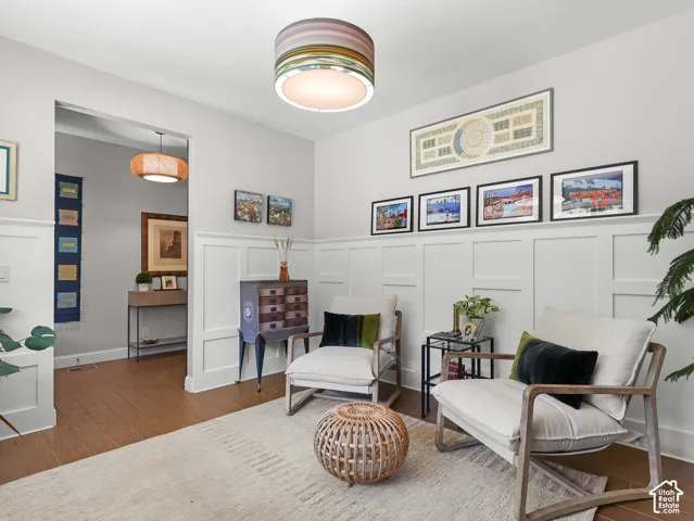 Board and batten wainscoting, wood-finish flooring, overhead drum pendant light, and a second pendant light in the doorway