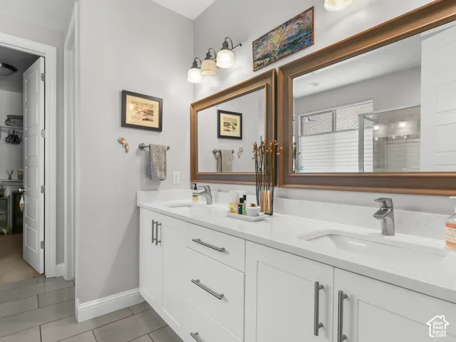 Dual vanity with white cabinetry, integrated sinks, chrome fixtures, and framed mirrors