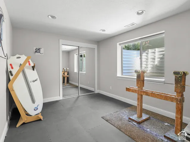 Recessed ceiling lights illuminate the space, featuring a window with a well-cover and mirrored closet doors