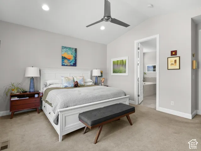 Vaulted ceiling with a ceiling fan, recessed lighting, carpet flooring, and a doorway to a bathroom with a built-in tub