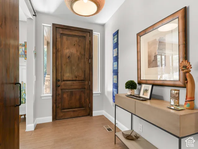 Wood-finish flooring, rich wood-panel door, built-in shelving, and transom window