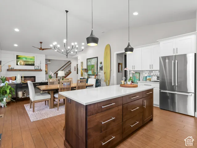 Kitchen featuring a wood-finish island with a light-toned countertop, white cabinetry with silver hardware, and a stainless steel refrigerator