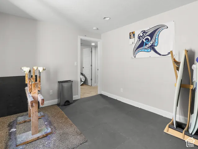Recessed lighting, light gray wall paint, white trim, and a door opening to an additional room