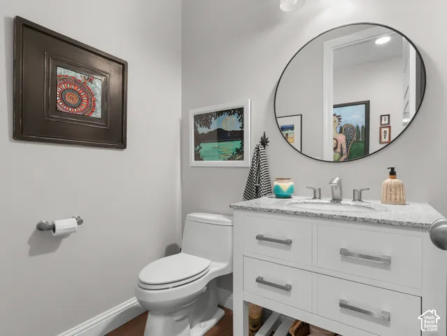 White vanity with brushed nickel hardware, speckled countertop, undermount sink, and a circular framed mirror