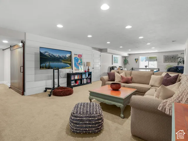 Recessed lighting, wood-finish barn door, shiplap accent wall, carpeted flooring, and a multi-panel interior door