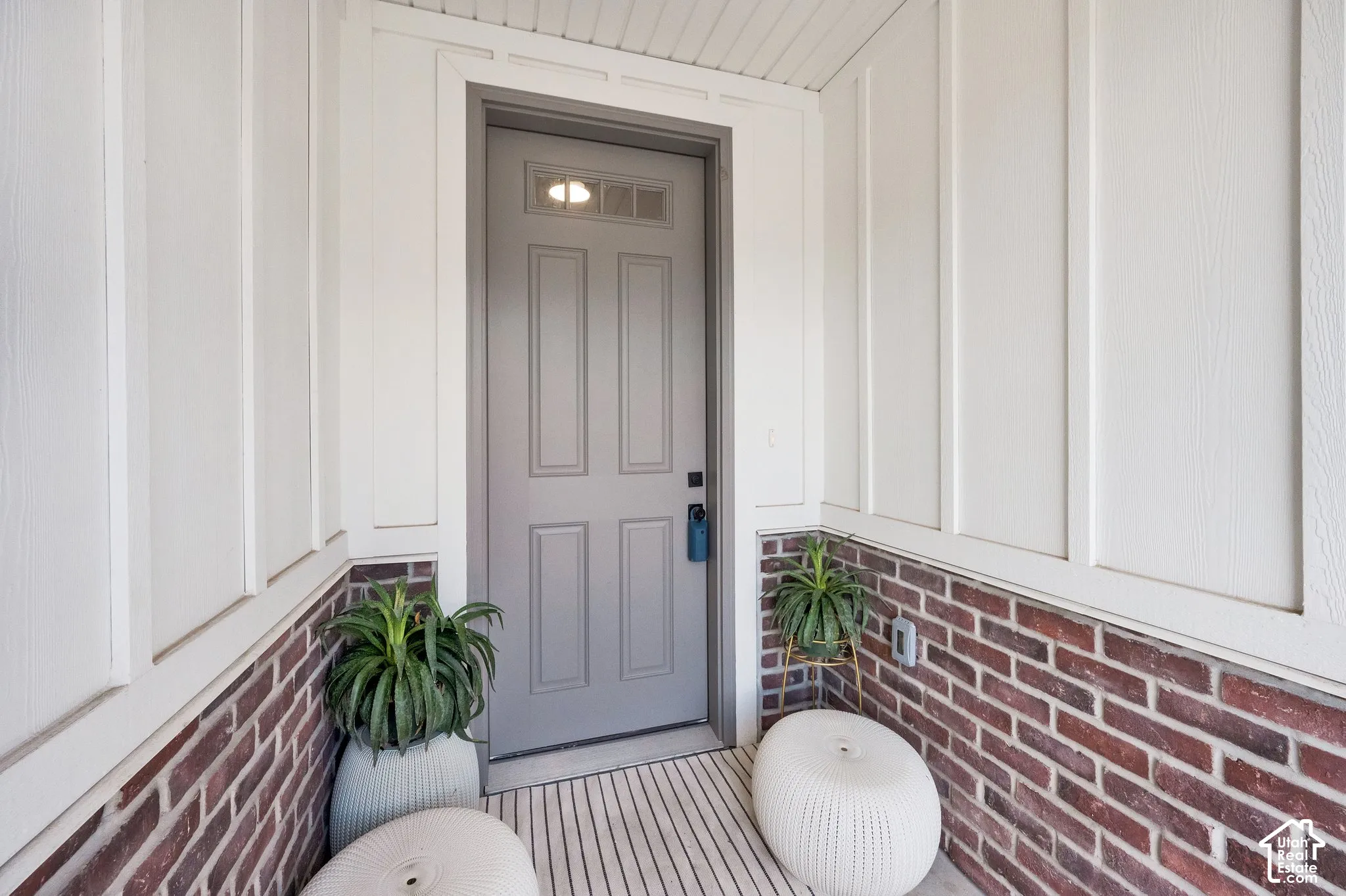 Entryway featuring a panel door with transom window, brick wainscoting, and vertical siding