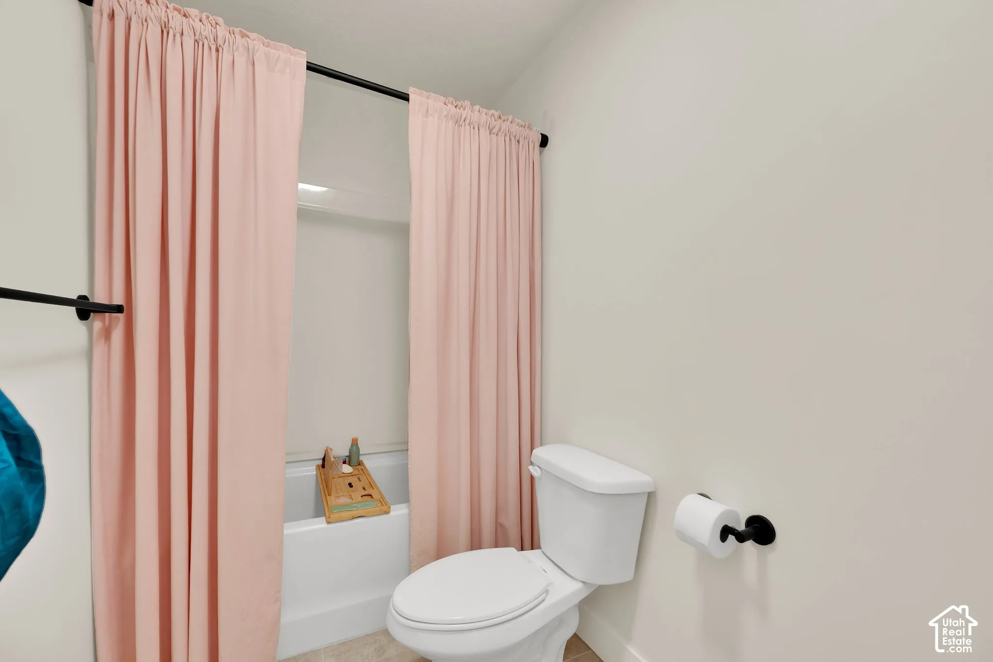 White toilet and bathtub with a black shower curtain rod and towel bar