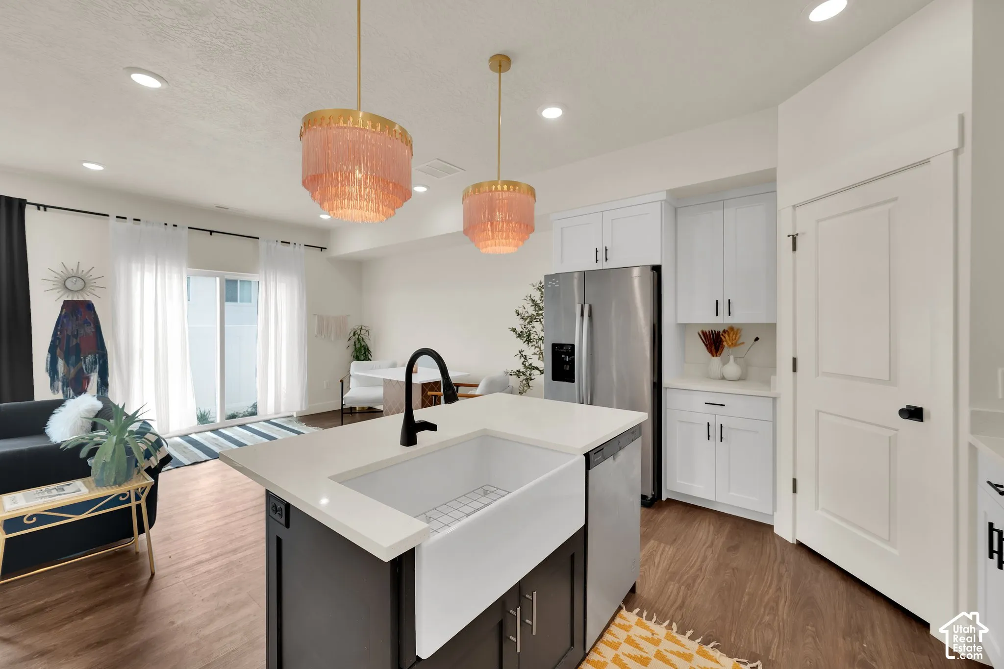 Modern kitchen island with a farmhouse sink, white countertops, and wood-finish flooring
