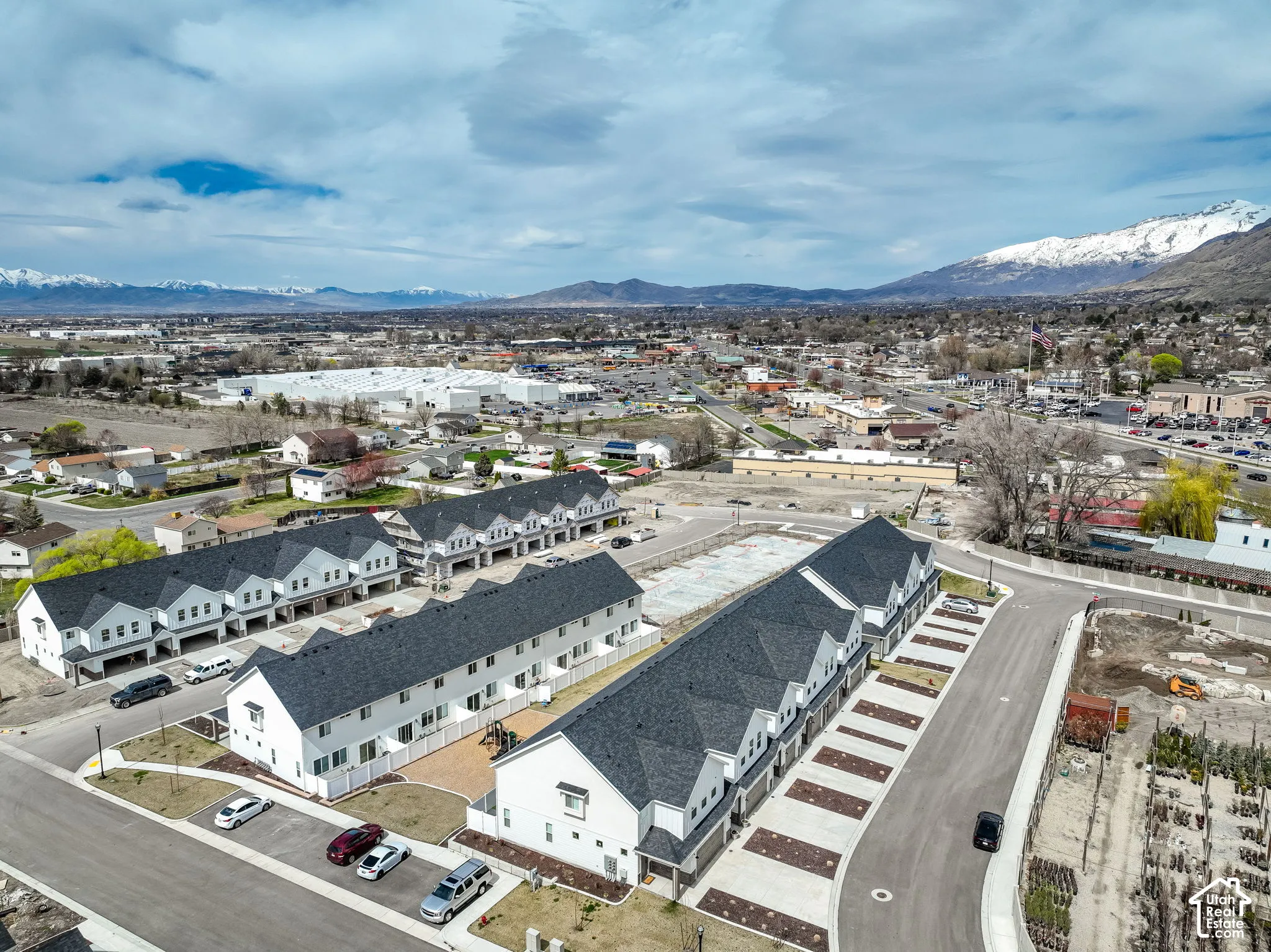 Modern townhome development with a pitched roofline, attached garages, and a paved parking area