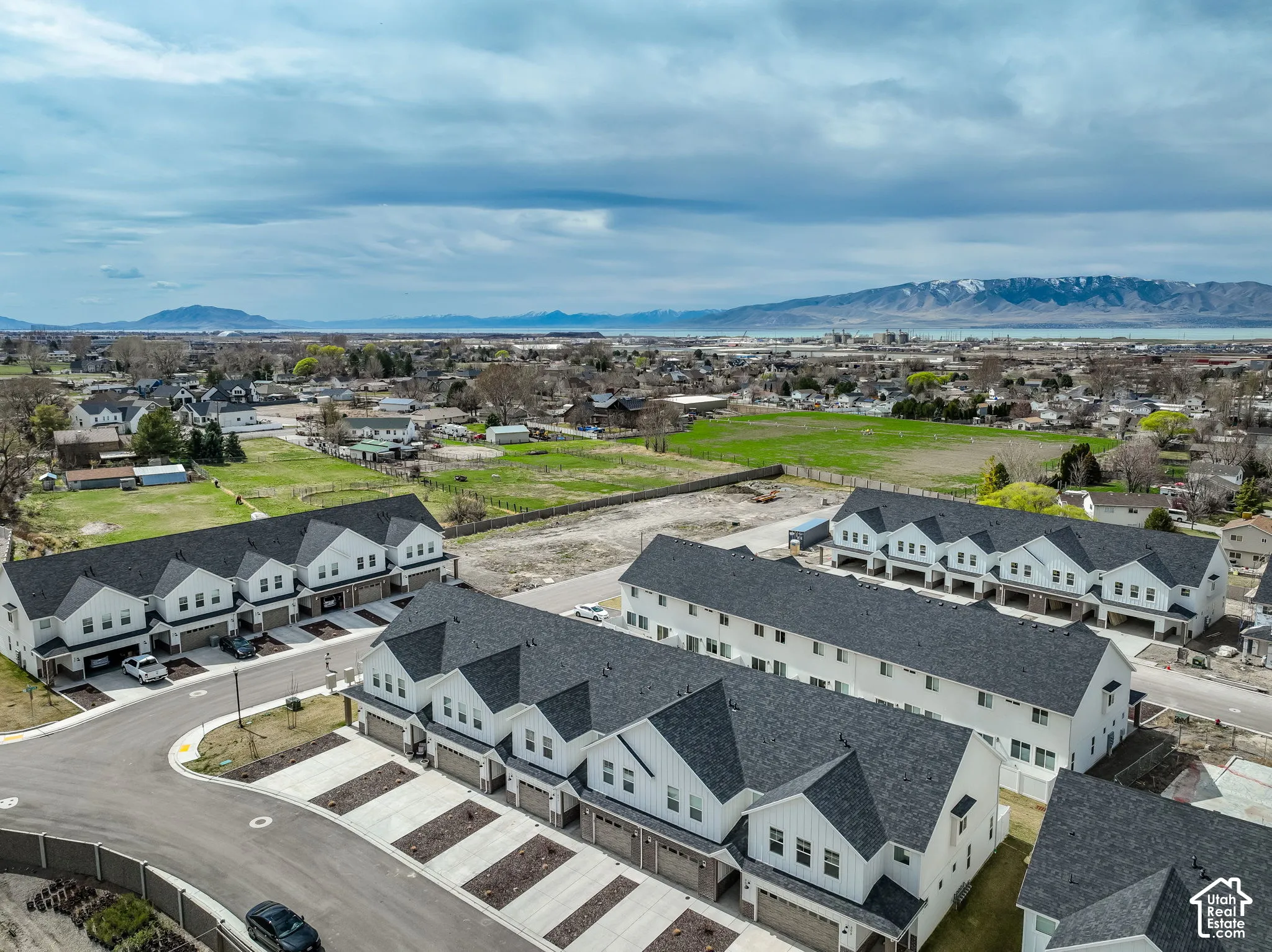 Modern townhome development with white facades, dark shingle roofs, and attached garages