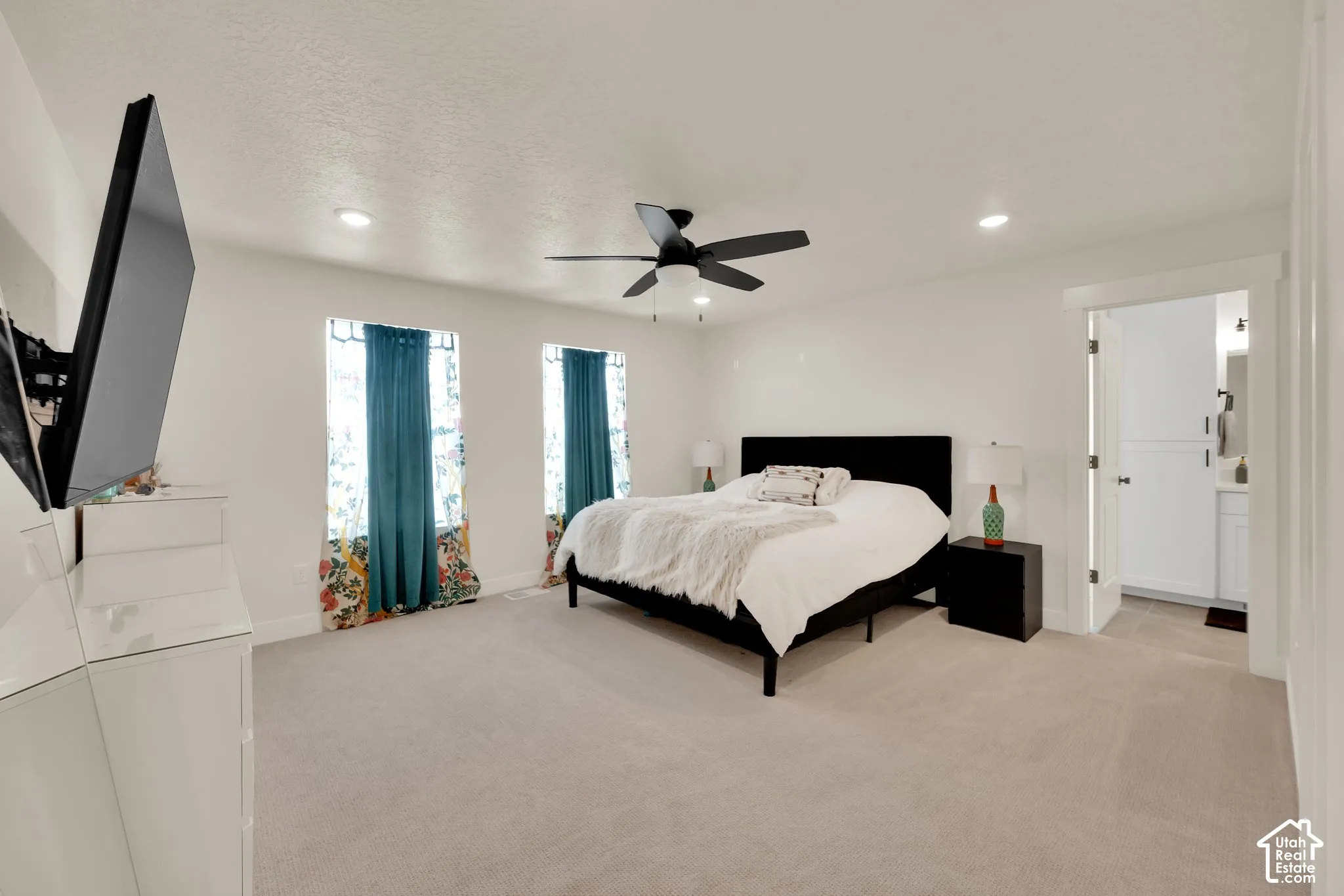 Spacious room with recessed lighting and a ceiling fan, featuring twin windows and carpeting