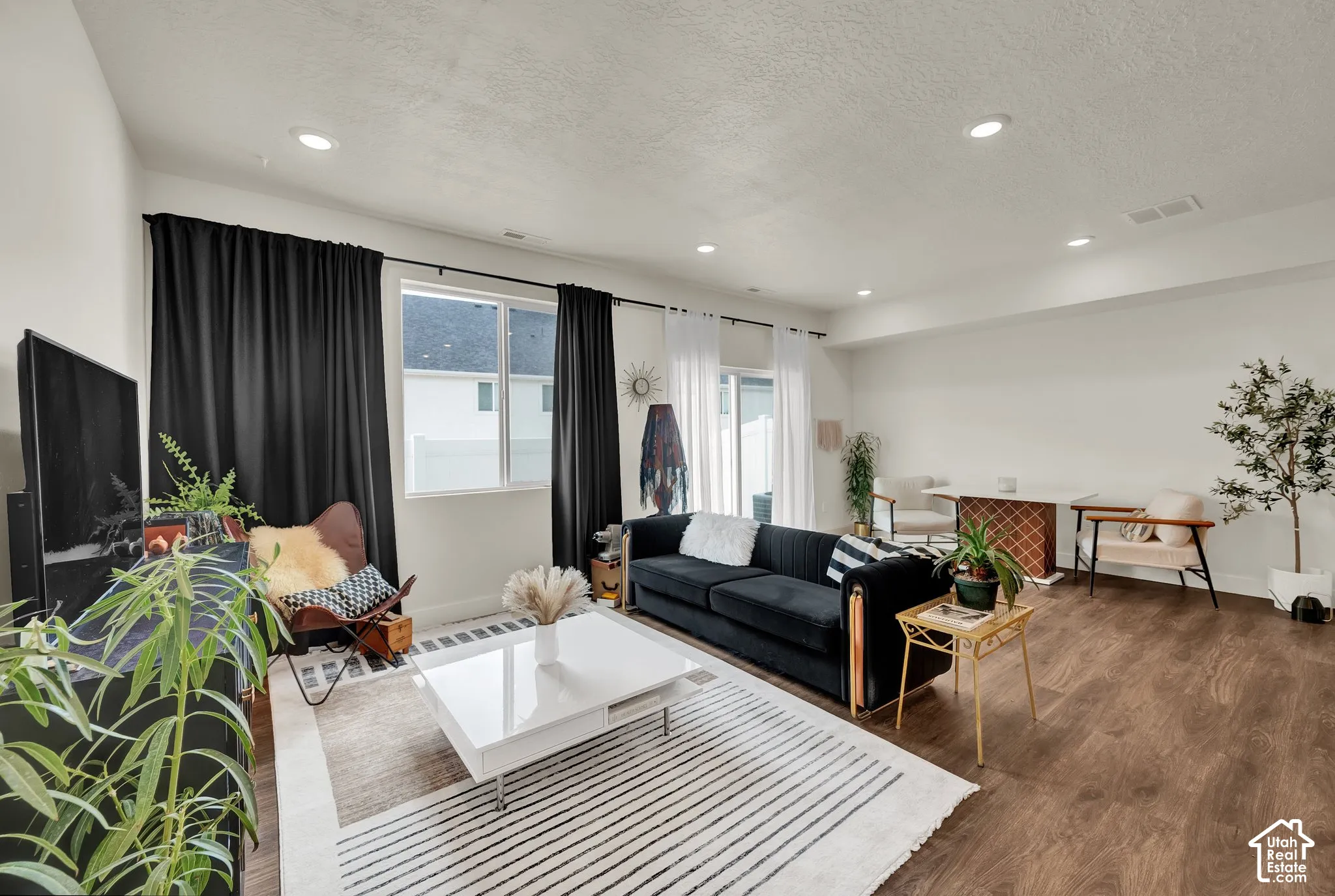 Spacious living area featuring wood-finish flooring, recessed lighting, and large windows