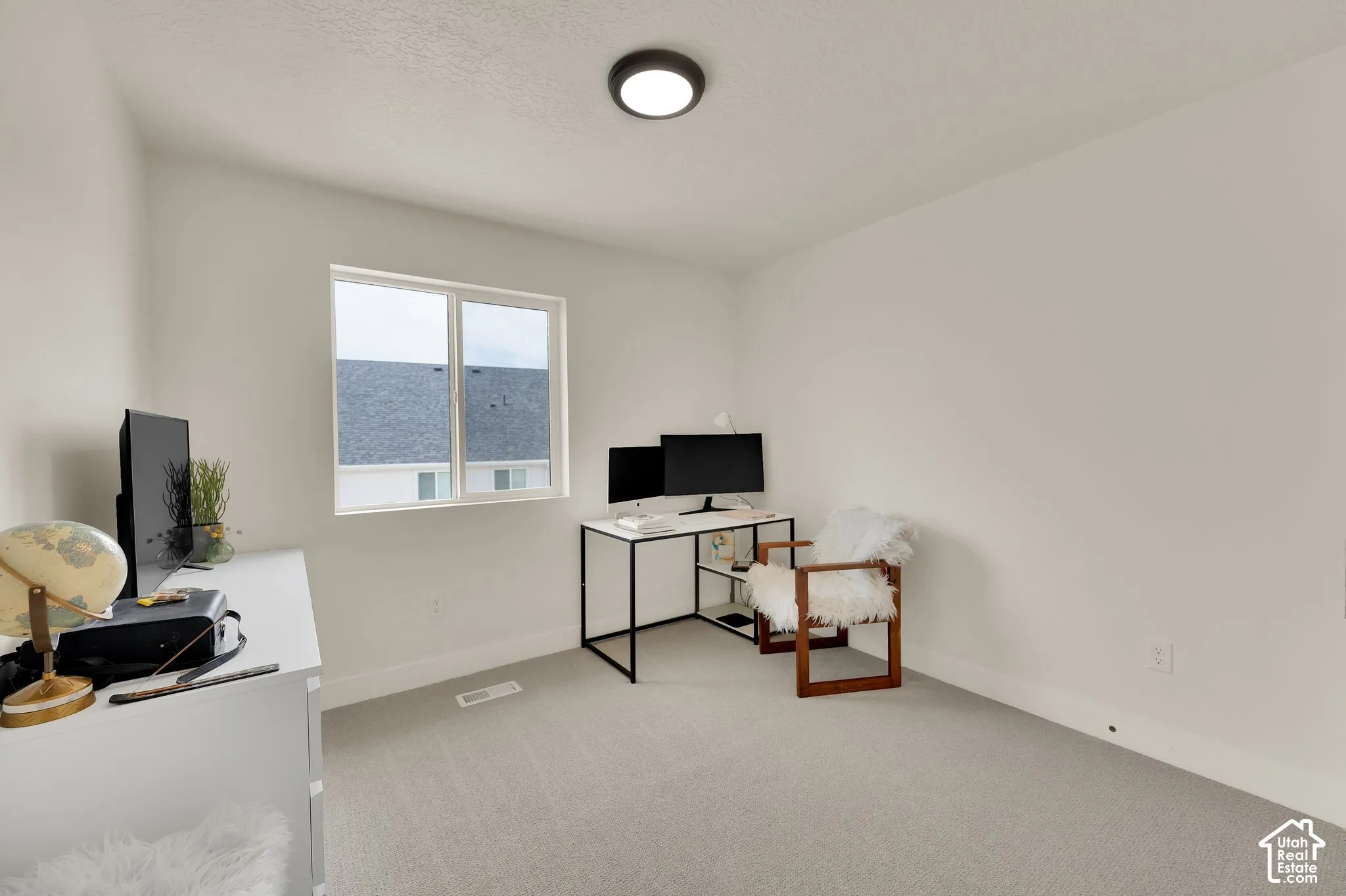 Neutral wall color with white trim, light-toned carpet, and a flush-mount ceiling light