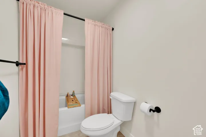 White toilet and bathtub with a black shower curtain rod and towel bar