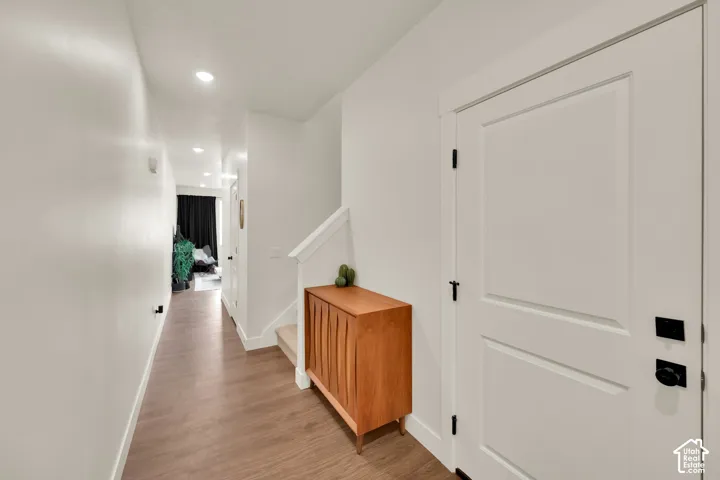 Hallway featuring wood-finish flooring, recessed lighting, and white trim