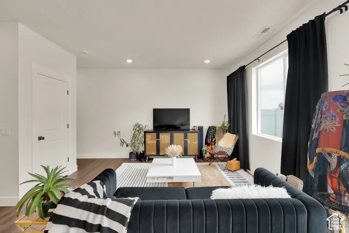 Recessed lighting, wood-finish flooring, white walls, and a large window